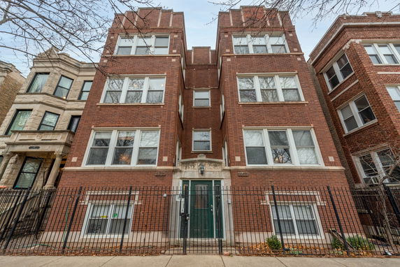 Front view of a brick multi-story apartment building with symmetrical windows.