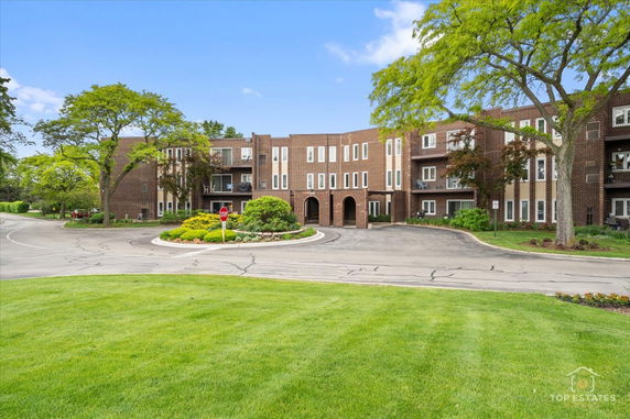 Front view of a multi-story brick apartment building with balconies.