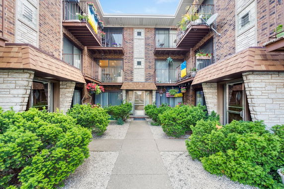 Front view of a multi-story residential building with balconies and brick facade.