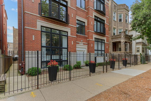 Front view of a multi-story apartment building with brick exterior and balconies.