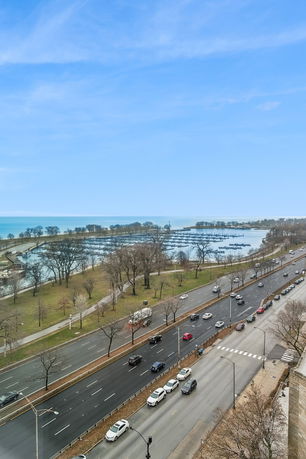 Panoramic view overlooking a highway, park, and a marina with water in the background.
