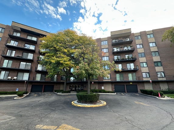 Front view of a multi-story brick building with balconies and garage units at ground level.