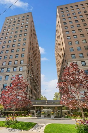 Front view of two tall adjacent apartment buildings with numerous windows.