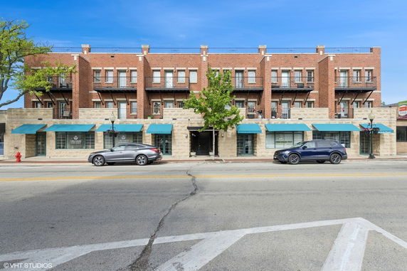 Front view of a multi-story brick building with blue awnings and balconies.