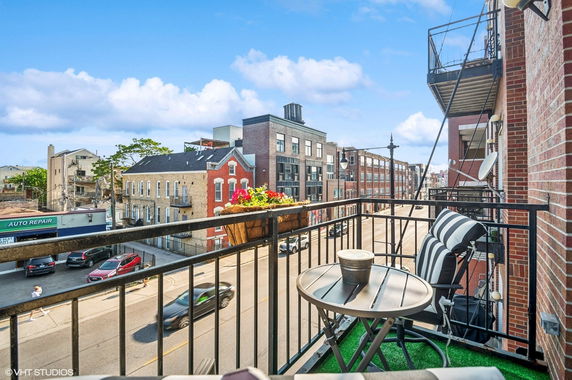 View from a balcony overlooking a street with buildings and cars.