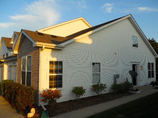 Front view of a single-story house with white siding and brick accent.