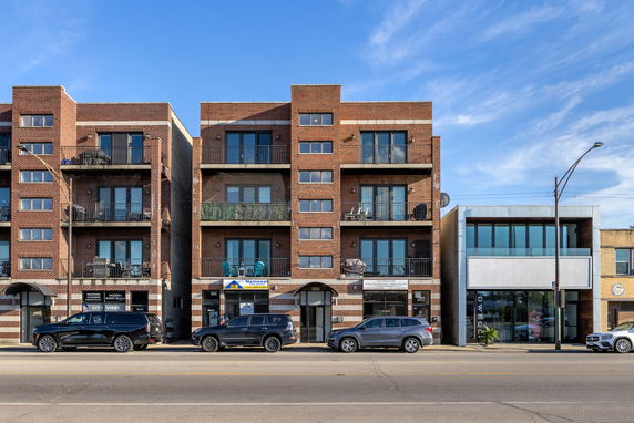 Front view of brick apartment buildings with multiple balconies and large windows.