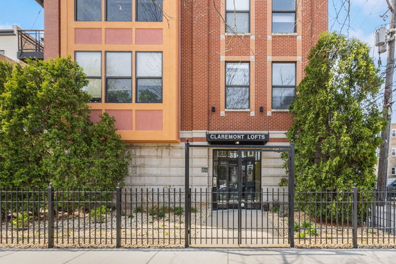 Front view of a multi-story building with brick exterior and gated entrance.