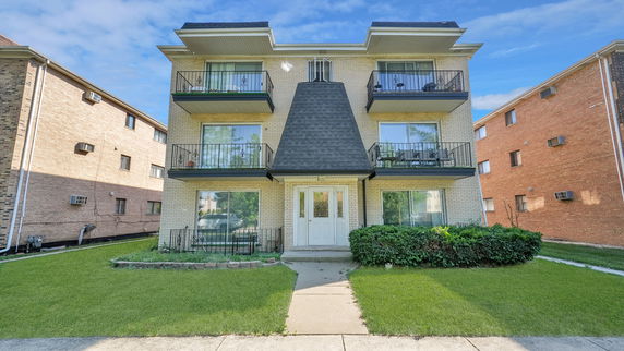 Front view of a three-story apartment building with balconies.