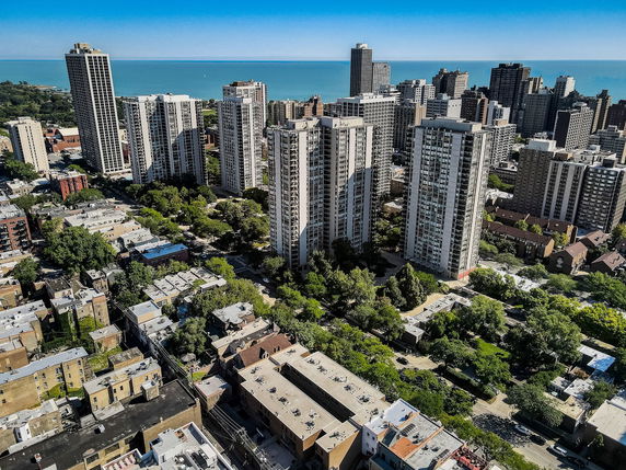Wide angle view of tall buildings in a cityscape near a large body of water.