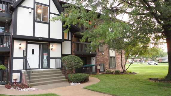Front view of a multi-story building with a brick and stucco exterior and balconies.