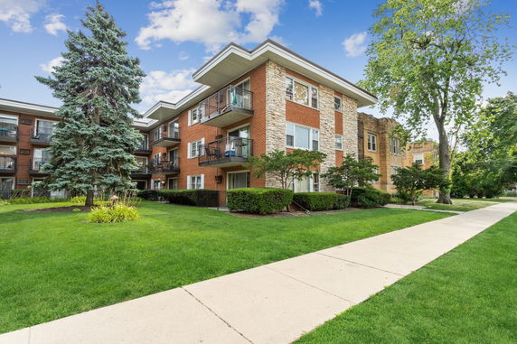 Front view of a multi-story brick apartment building with balconies.