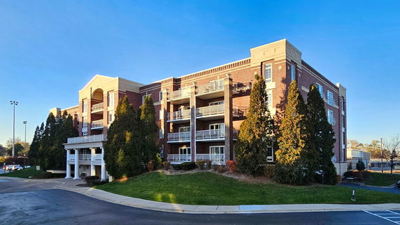 Front view of a multi-story brick apartment building with balconies.