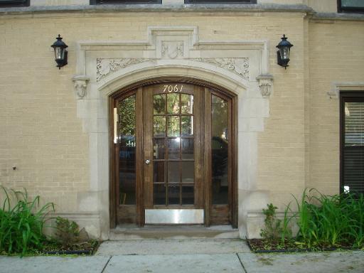 Front view of a building entrance with ornate stonework and glass doors.