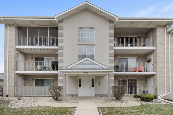 Front view of a three-story apartment building with balconies.