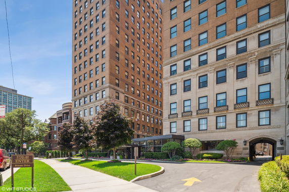 Front view of a tall, multi-story building with a private driveway and landscaped entrance.