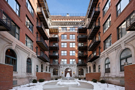Front view of a multi-story brick residential building with balconies and arched windows.