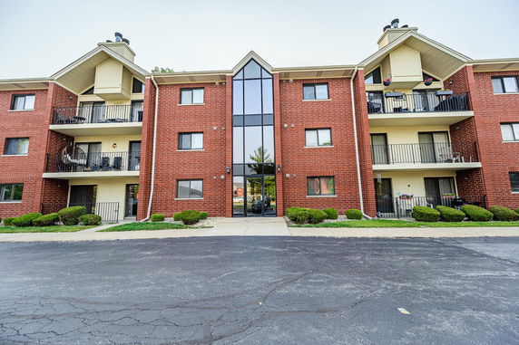 Front view of a multi-story brick apartment building with balconies.