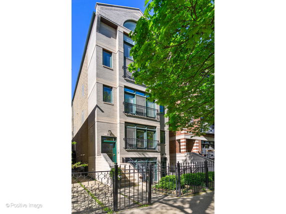 Front view of a multi-story residential building with balconies and a gated entrance.
