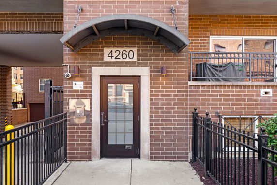 Front view of a brick building entrance with glass door and an awning above.