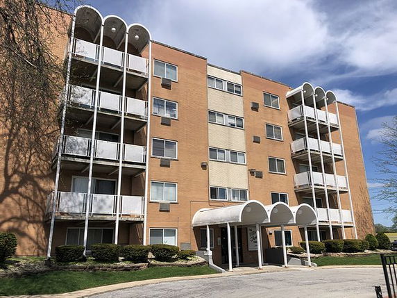 Front view of a four-story apartment building with balconies.