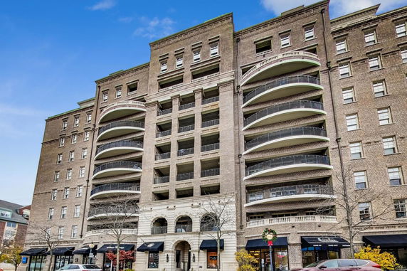 Front view of a multi-story brick building with balconies and arched entrance.