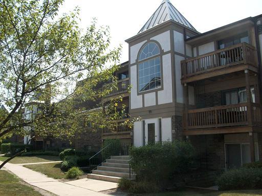 Front view of an apartment building with balconies and a large arched window.