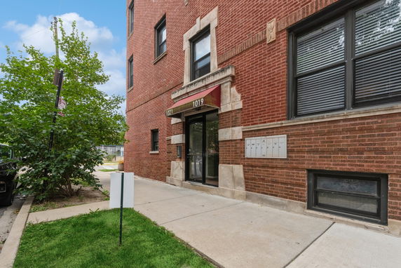 Front view of a brick building entrance with a red canopy.