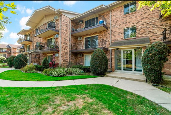 Front view of a multi-story brick apartment building with balconies.