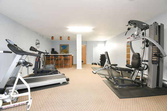 Interior view of a gym room with exercise equipment including a treadmill and stationary bike.