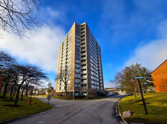 Front view of a tall residential building with multiple balconies.