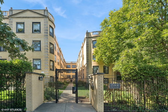 Front view of a multi-story apartment building with a gated entrance.