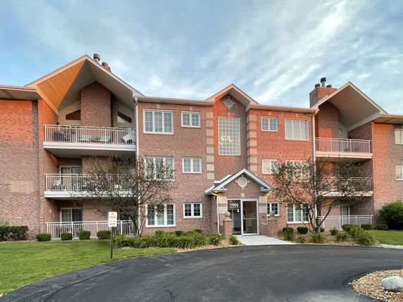 Front view of a three-story apartment building with balconies and a central entrance.