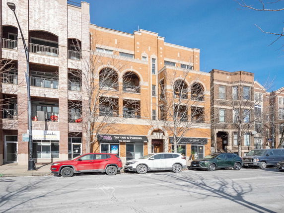 Front view of a multi-story building with retail spaces on the ground floor.