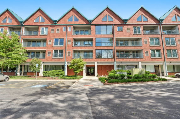 Front view of a multi-story brick residential building with balconies and triangular roof design.