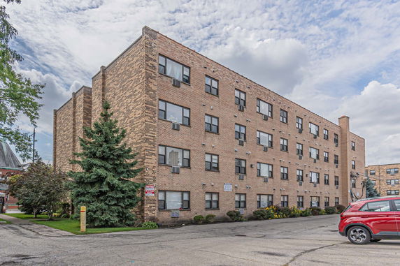 Front view of a four-story brick apartment building with multiple windows.