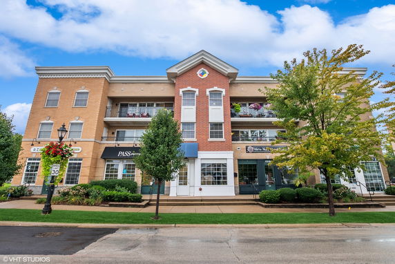 Front view of a multi-story commercial building with brick facade and shops on the ground floor.
