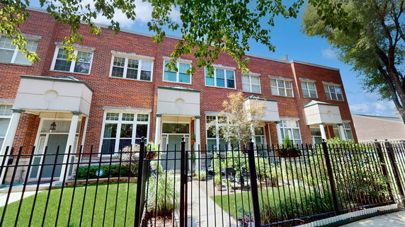 Front view of a multi-story brick row house with a gated entrance.
