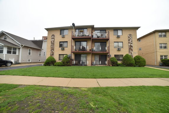 Front view of a three-story apartment building with balconies and stone accents.