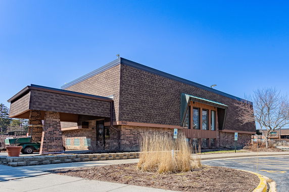 Front view of a modern building with a unique architectural design featuring brick facade and angled roof sections.