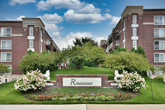 Front view of a multi-story brick building with landscaped entrance.