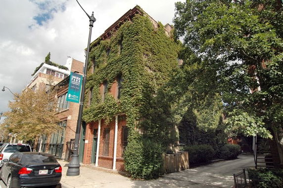 Front view of a brick building covered with ivy.