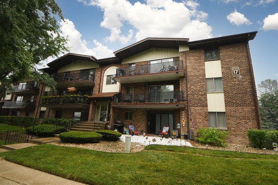 Front view of a multi-story apartment building with balconies and a brick exterior.