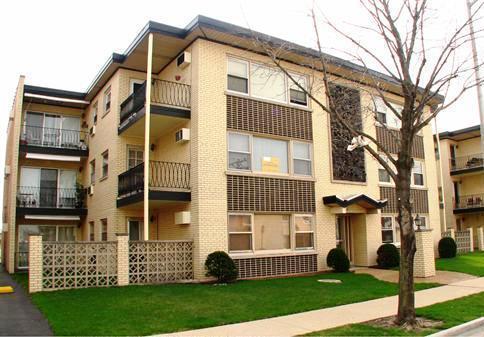 Front view of a three-story apartment building with balconies and a brick exterior.
