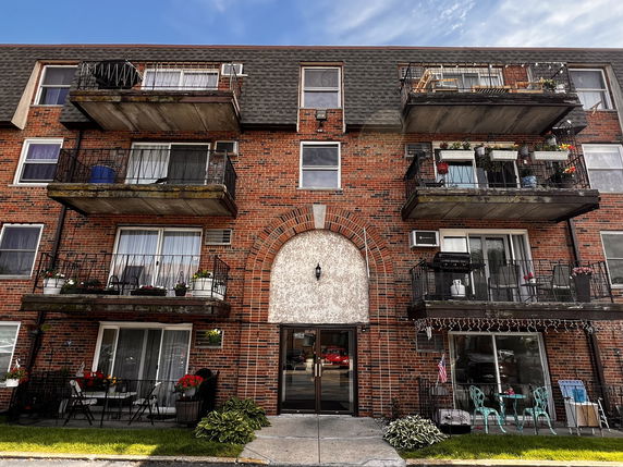 Front view of a multi-story brick apartment building with balconies.