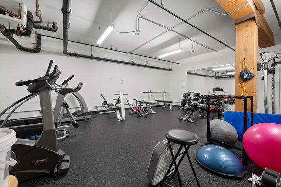 Indoor gym area with various fitness equipment and exercise balls.