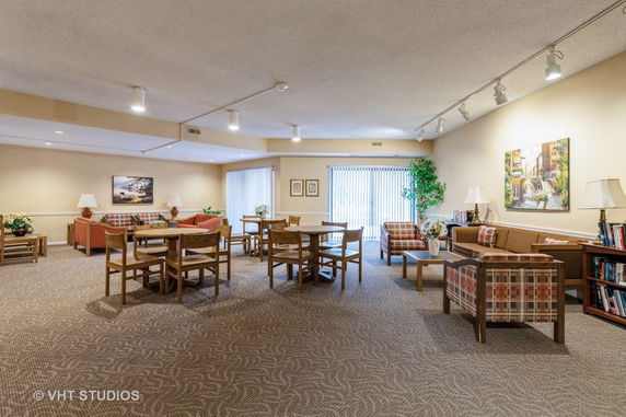 Interior room with tables, chairs, sofas, and bookshelves in a recreational setting.