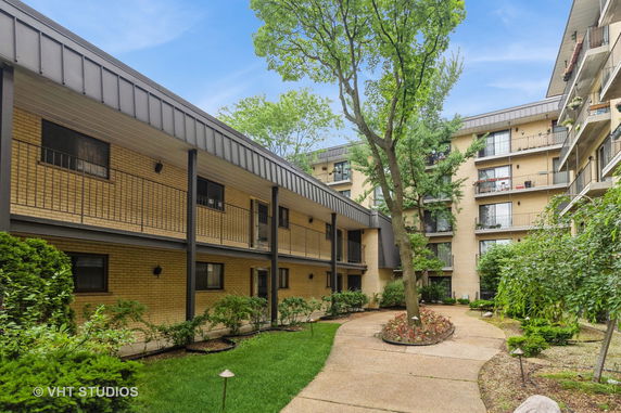 Front view of a multi-story apartment building with balconies and a courtyard.