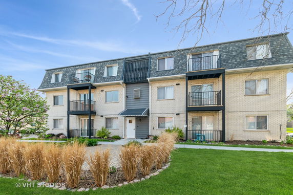 Front view of a multi-story building with balconies and a gable roof.