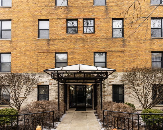 Front view of a multi-story brick apartment building with an entrance canopy.